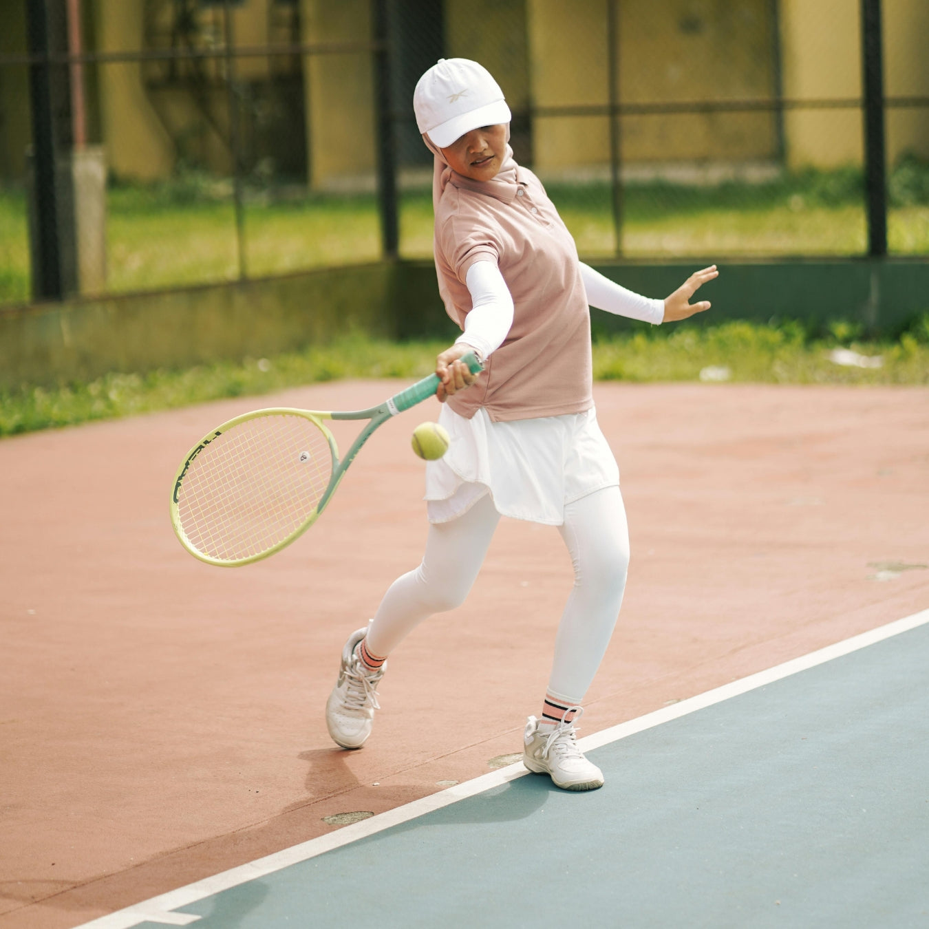 Person playing tennis on a court with a racket and ball