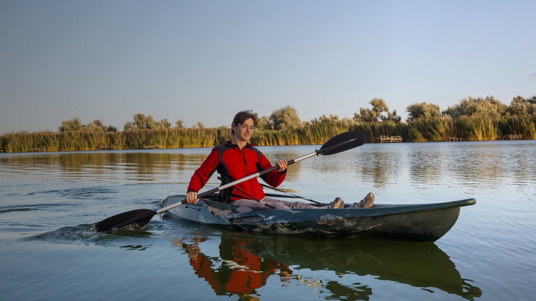Person kayaking on a calm lake with trees in the background